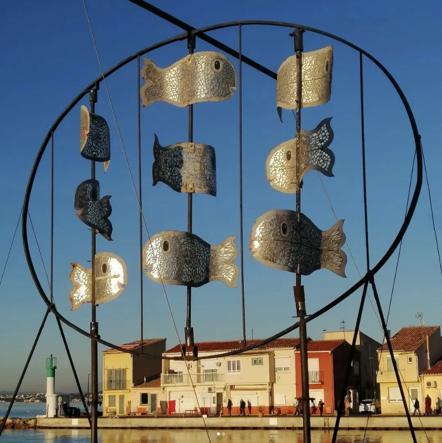 Les célèbres daurades miroirs de la sculpture de Dominique Doré, installée en 2009, flottent à nouveau dans l'air, ondulant comme elles le feraient dans la lagune toute proche.
